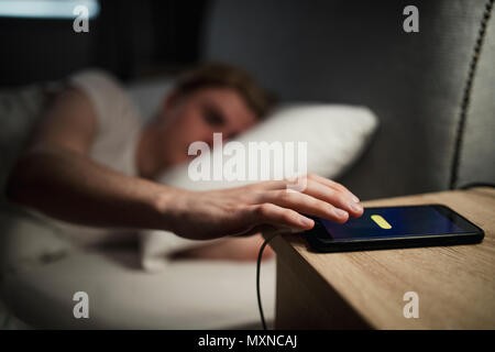 Jungen Erwachsenen männlichen Kämpfen am Morgen aufwachen, schlagen die Funktion für eine erneute Erinnerung seine Warnung. Stockfoto