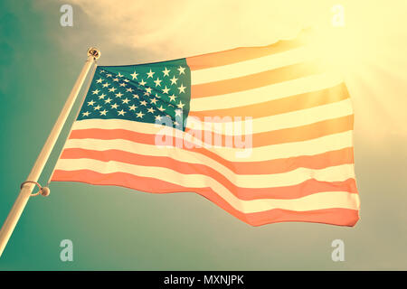 Amerikanische Flagge auf einer Stange in den Wind, Sonne und blauer Himmel, vintage Prozess Stockfoto