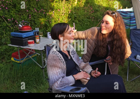 Eine Tochter gilt Make-up zu ihrer Mutter auf einem Campingplatz. Stockfoto