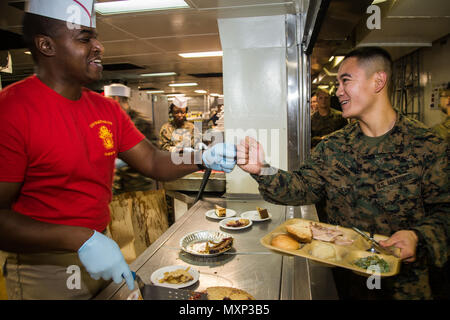 USS Makin Island, im Indischen Ozean (24. November 2016) eine Marine und Sailor mit der Makin Island Amphibious Ready Gruppe/11 Marine Expeditionary Unit, wünschen einander ein Happy Thanksgiving Tag bei einem Abendessen in Einhaltung der Urlaub an Bord der USS Makin Island (LL 8), Nov. 24, 2016 statt. Die schiffsführung Thanksgiving Day Feierlichkeiten bestand aus einem fünf Kilometer laufen und ein Abendessen, das die Marines und Segler die Möglichkeit, eine Pause zu nehmen und den Urlaub zusammen beobachten erlaubt. (U.S. Marine Corps Foto von Cpl. Devan K. Gowans/Freigegeben) Stockfoto