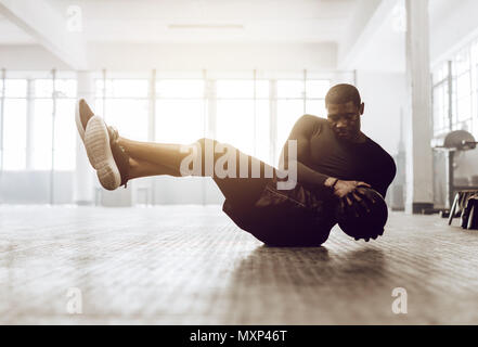 Athletischer Mann tun Bauch Übung auf dem Boden. Mann tun crossfit Workout mit einem medizinball in der Turnhalle. Stockfoto