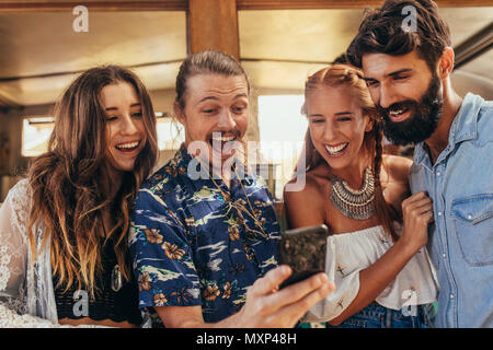 Lächelnden jungen Menschen unter selfie mit Handy. Lachende junge Männer und eine Frau unter selfie Bild mit Smart Phone. Stockfoto