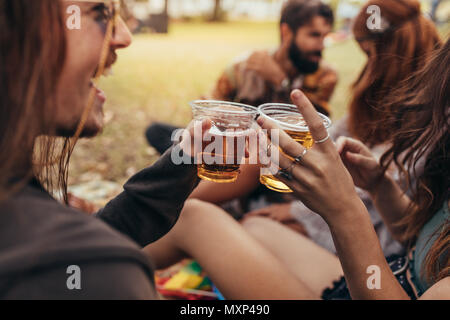 Nahaufnahme von Paar Hände Schiebeschalter ein Glas Bier mit Freunden an der Rückseite. Gruppe von Menschen Bier im Sommer Festival. Stockfoto