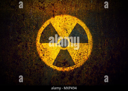 Runde gelbe Radioaktivität (ionisierende Strahlung) Gefahrensymbol malte auf eine massive rostiges Metall Wand mit dunklen rustikalen Grunge Texturen Hintergrund mit vign Stockfoto