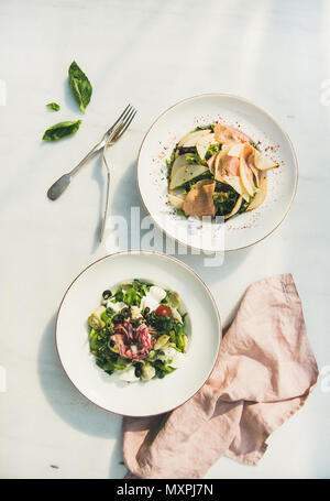 Frische grüne Sommersalate in weißen Platten, Ansicht von oben Stockfoto