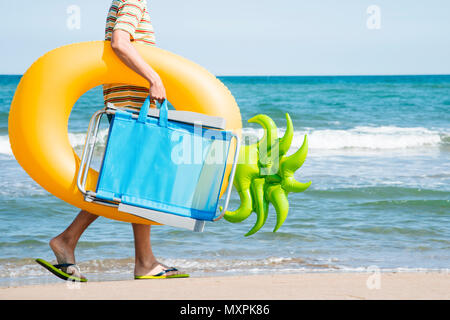 Nahaufnahme eines jungen kaukasischen Mann an der Küste, mit einem Strandkorb und eine Swim Ring in der Form einer Ananas, oder zurück von der werden. Stockfoto