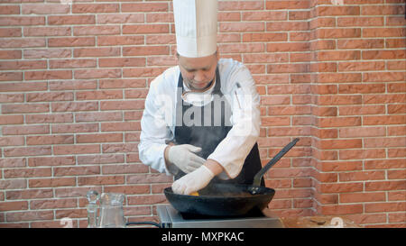 Küchenchef im Restaurant kochen gebratene Knödel mit Meeresfrüchten in Pan, Zitronensaft zusammendrücken. Stockfoto