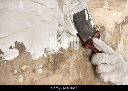 Hand in Hand verputzen Betonwand mit Spachtel während der Reparatur Stockfoto