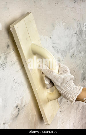 Hand mit Kelle verputzen Betonwand während der Reparatur Stockfoto