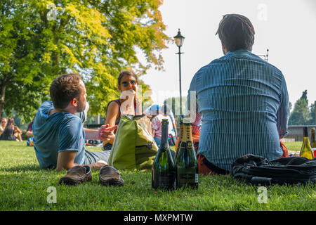 Freunde genießen das gute Wetter und ein Picknick im Park an der Gemeinde Gärten in Hammersmith in London, Großbritannien, haben Stockfoto
