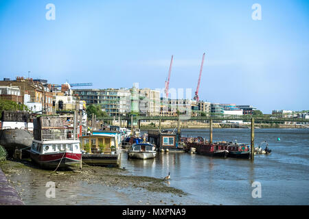 Ein Blick auf die Themse Richtung Hammersmith Bridge in London. Es ist Ebbe und angelegten Boote sind auf dem Schlamm des Flusses Bett Strände. Stockfoto