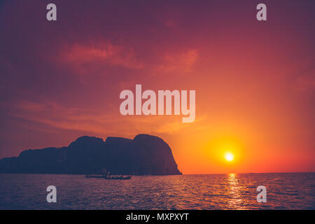 Atemberaubenden Sonnenuntergang über dem Meer und Kalkfelsen Neben dem exotischen Phi Phi Islands, dem Königreich Thailand. Erstaunliche Himmel im Golden, Orange und Purpur Reflexen. Stockfoto