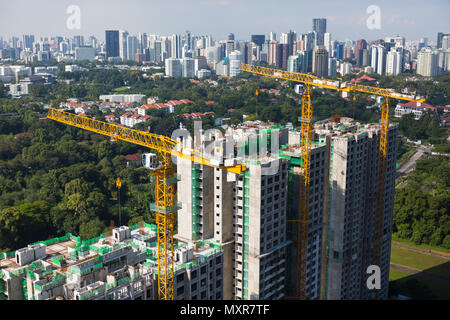 Nahaufnahme von drei gelben Turmkränen im urbanen Bereich von Wohnsiedlungen. Singapur Stockfoto