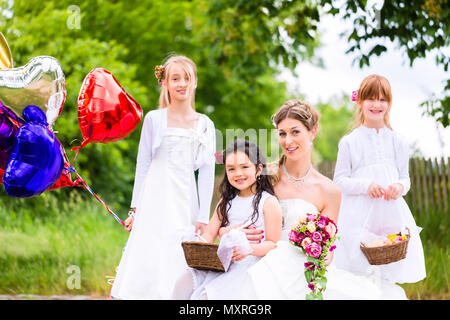 Braut mit Mädchen als Brautjungfern, Blumen und Ballons Stockfoto