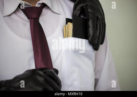 Ein Dieb nimmt ein Portemonnaie mit Bargeld aus einer Tasche eines Mann im Anzug, ein Geschäftsmann, ein Verbrechen, eine Tasche Stockfoto