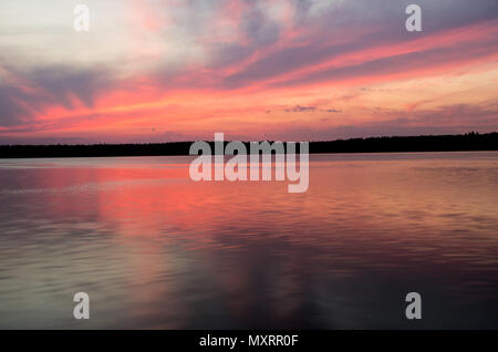 See gegen bunte Himmel mit Wolken und Felsen bei Sonnenuntergang im Sommer. Stockfoto