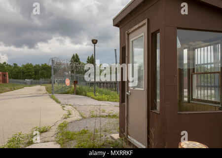 Die Außenseite des Gefängnis Pförtnerloge durch Zaun mit Stacheldraht mit Hof mit Unkraut überwucherten umgeben. Stockfoto