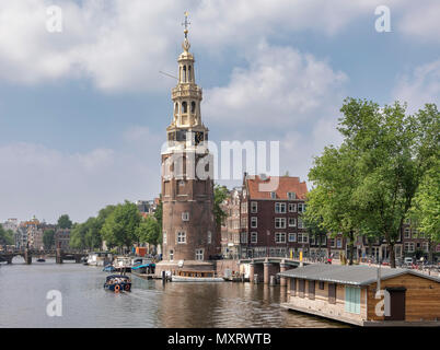 AMSTERDAM, NIEDERLANDE - 30. Mai: ein Ausflugsboot, der vergehen muss, bevor die Montelbaanstoren Turm an der Oudeschans Canal am 30. Mai 2018 in Amsterdam, Niederlande. Der ursprüngliche Turm wurde 1516 als Teil der Wände von Amsterdam zur Verteidigung der Stadt und dem Hafen gebaut. Stockfoto