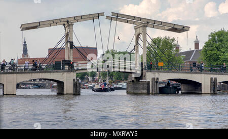 AMSTERDAM, NIEDERLANDE - 30. Mai: Sightseeing Boote unter der Magere Brug Brücke am 30. Mai 2018 in Amsterdam, Niederlande. Diese bewegliche Brücke über den Fluss Amstel ist der bekannteste der 1.753 Brücken in der Stadt. Stockfoto