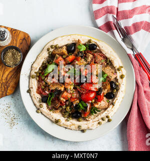 Vegan panzanella Salat auf einer Schicht von Hummus auf einem Teller. Leckeres und gesundes Essen. Stockfoto