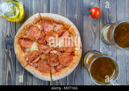 Pizza mit zwei Gläsern Bier auf braune Holztisch. Stockfoto