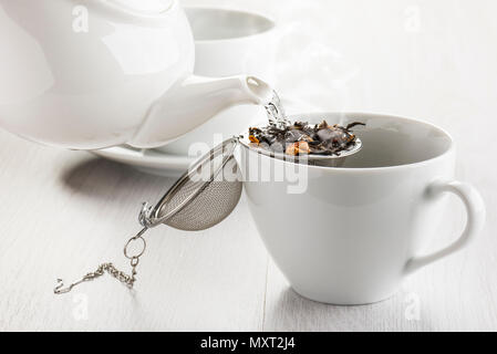 Strömenden heißen Wasser auf Tee-ei in weiße Schale. Stockfoto