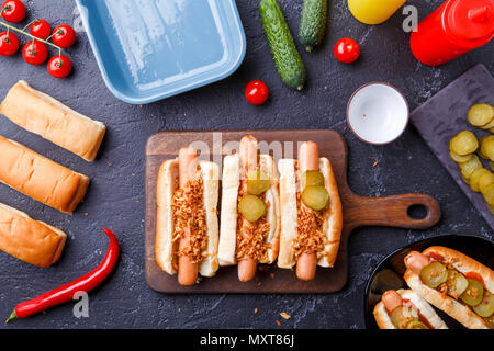 Bild oben auf Brötchen mit Wurst auf Schneidebrett, auf Tabelle mit Gurken Stockfoto