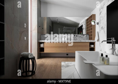 Badezimmer in einem modernen Stil mit hellen Wänden. Es ist ein Fliesen- zone mit einer weißen Badewanne mit Chrom Wasserhahn, Waschbecken mit Spiegel und Schließfächer und Nischen, Holz Stockfoto