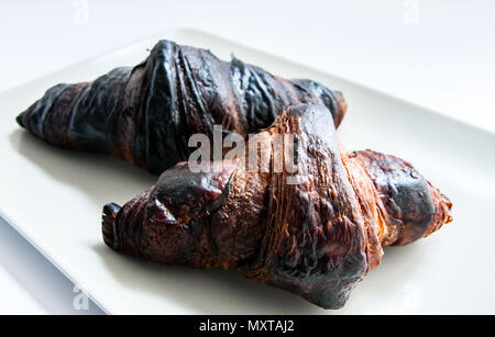 Zwei verbrannte Croissants auf einer Platte Stockfoto