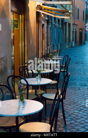 Kleine Kopfsteinpflasterstraße in Rom mit Tischen und Stühlen am Abend Stockfoto