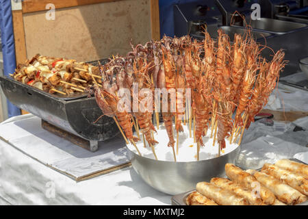 Die Tabelle im Kiosk an der Asiatischen Street Food Festival. Die Straße stand mit Angebot an asiatischen Speisen, Grill mit Kebab und Schüssel mit Meeresfrüchten, Sepia und lobste Stockfoto