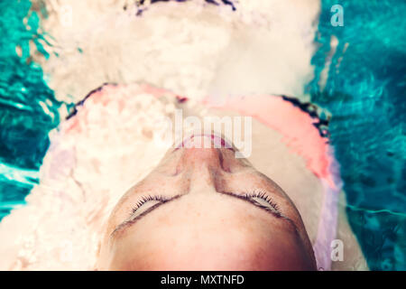Schöne Frau Relaxen im Pool, türkisfarbenem Wasser geschlossenen Augen Genuss spa Behandlung Konzept Stockfoto