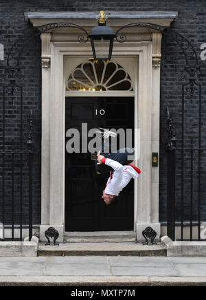 Gymnast Dominick Cunningham führt einen Rückwärtssalto auf die Schritte der 10 Downing Street, London. Stockfoto