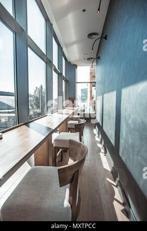 Gemütliche Einrichtung des modernen Restaurant. Im inneren Teil der Halle mit der Reihe von Barhockern und lange Bar Tisch vor transparentem Glas Fenster. Herrlichen Panoramablick. Stockfoto