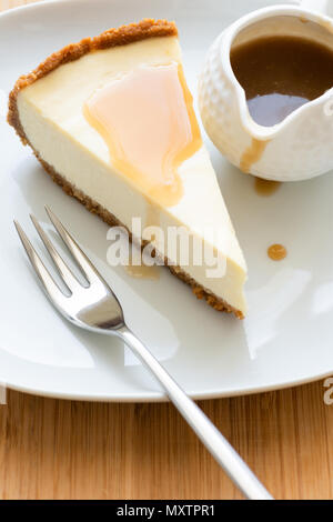 Scheibe des klassischen New York Cheesecake mit Karamellsauce. Detailansicht, selektiver Fokus Stockfoto