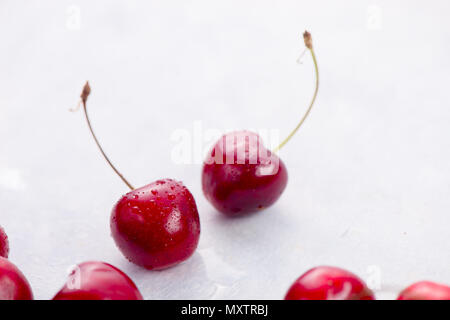 Zwei süße Kirschen mit Wassertropfen auf einem weißen Hintergrund. Makro Beeren shot mit Kopie Raum Stockfoto