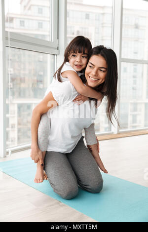 Foto fröhliche Familie Mutter und Kind Spaß haben, während die Frau ihre Tochter indoor Netzwerk zugreift. Stockfoto