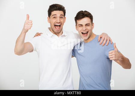 Foto von zwei männlichen Freunde 30 s legere T-Shirt und Jeans lächelnd und mit Daumen oben auf der Kamera auf weißem Hintergrund Stockfoto