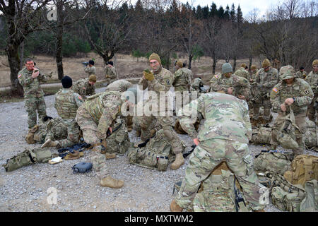 Fallschirmjäger der 1. Geschwader, 91. Kavallerie-Regiment, 173. Luftlandebrigade, bereiten sich während der Übung Mountain Shock auf eine Feuerübung in der Pocek Range vor. Soldaten tragen Tarnfarbe auf und üben taktischen Einsatz, wobei sie die schnelle Zusammenstellung von Truppen, Koordination und Teamzusammenhalt betonen. Die Übung verbessert die Interoperabilität, die Bereitschaft und die Notfallreaktionsfähigkeiten der alliierten NATO-Streitkräfte, wobei neben slowenischen Militäreinheiten Schulungen durchgeführt werden. Stockfoto