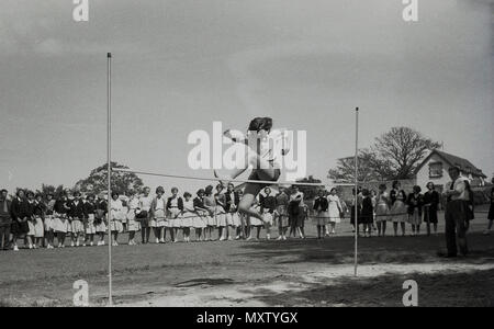 1960, historische Bild von sekundären schoogirl in einem inter-Schule county Sports Day, Dorset, England, UK. Hier sehen wir Sie tun im Hochsprung mit einer eher individuellen Stil passte durch eine Linie von spectatotrs. Stockfoto