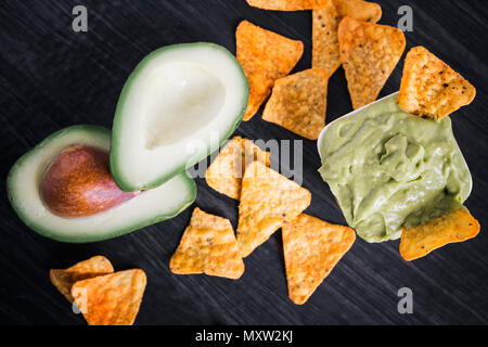Avocado und guacamole Dip mit Tortilla Chips auf einem dunklen Hintergrund Stockfoto