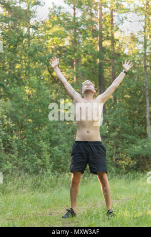 Mitte Barechested nach 40 s kaukasischen Mann, der oben am Himmel mit der Arme über den Kopf angehoben suchen Stockfoto