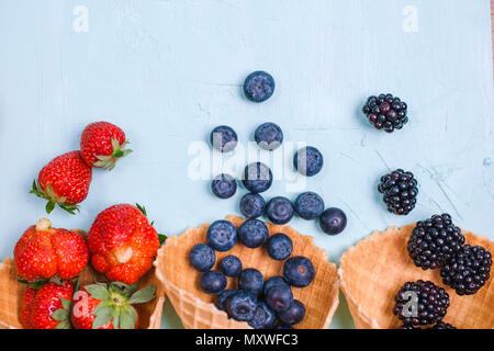 Verschiedene Beeren und Früchte auf einem blauen Hintergrund. Freier Platz für Text. Kopieren Sie Platz. Flach Stockfoto