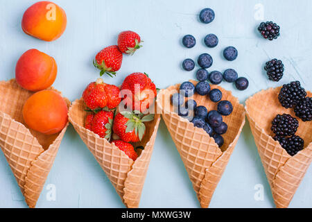 Verschiedene Beeren und Früchte auf einem blauen Hintergrund. Freier Platz für Text. Kopieren Sie Platz. Flach Stockfoto