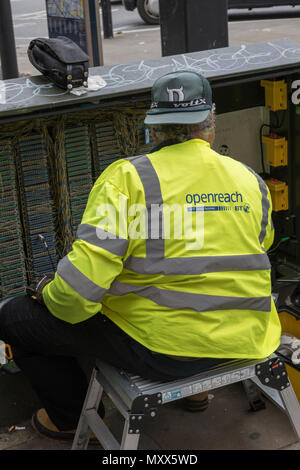 Ein BT British Telecom Arbeitnehmer in einem offenen Telekommunikation Kabinett die Durchführung der Verkabelung und Wartung sitzen. Stockfoto