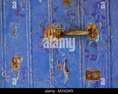 Die alte blaue geschmiedete Tür mit einem alten Metallgriff, manchmal rostig. Stockfoto