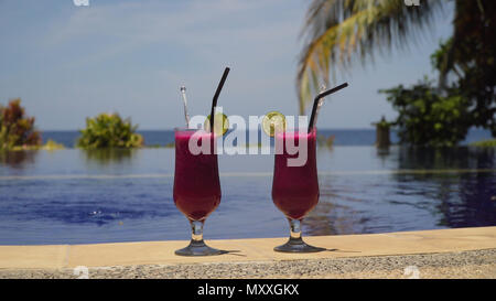 Zwei Gläser Cocktails auf dem Hintergrund der Pool, Meer, Palmen. Cocktails mit Drachenfrucht nahe dem Pool. Sommer Getränke, urlaub, reisen, ferienhäuser Konzept. Stockfoto