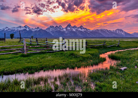 Golden feurigen Sonnenuntergang am Grand Teton - eine Feder Sonnenuntergang am Teton Range, von einem verlassenen Old Ranch in Mormonischen Reihe gesehen, im Grand Teton National Park, USA. Stockfoto