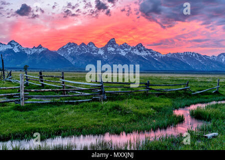 Teton auf Feuer - eine spektakuläre Frühjahr Sonnenuntergang am Teton Range, von einem verlassenen Old Ranch in Mormonischen Reihe gesehen, im Grand Teton National Park, Wyoming, USA. Stockfoto
