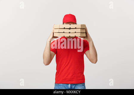 Ein Deliveryman hinter einem großen Stapel von pizzakartons Er trägt, versteckt. Über grauer Hintergrund isoliert. Stockfoto